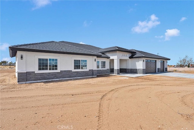 view of front facade featuring stone siding, concrete driveway, a garage, and stucco siding