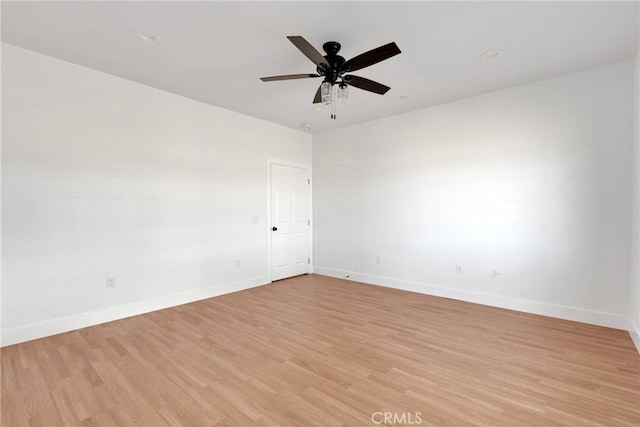 spare room featuring ceiling fan, light wood-style flooring, and baseboards