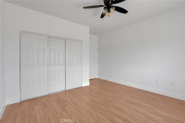 unfurnished bedroom with ceiling fan, light wood finished floors, a closet, and baseboards