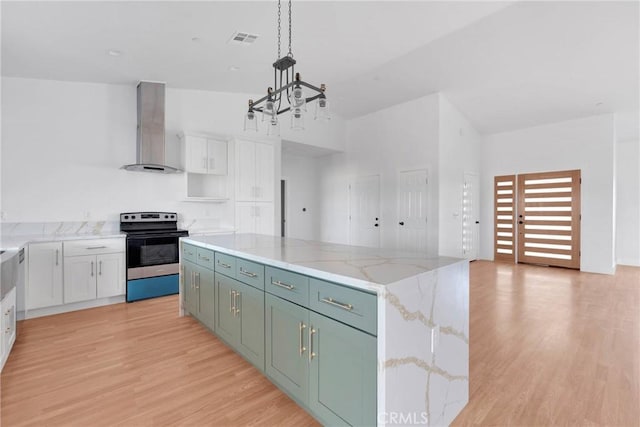 kitchen with electric stove, visible vents, wall chimney range hood, and white cabinets