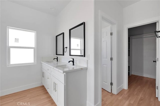 bathroom with wood finished floors, a sink, and baseboards