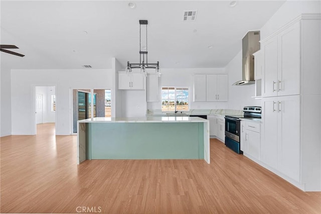 kitchen with electric range, visible vents, wall chimney exhaust hood, light countertops, and white cabinetry