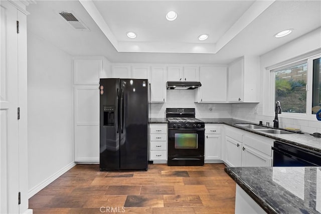 kitchen with under cabinet range hood, a sink, visible vents, black appliances, and a raised ceiling