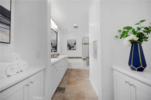 full bath with visible vents, stone finish flooring, a garden tub, a stall shower, and vanity