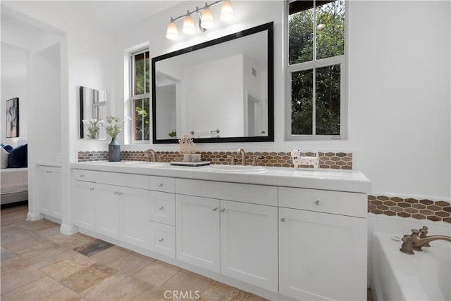 bathroom featuring ensuite bath, double vanity, a bathtub, and a sink