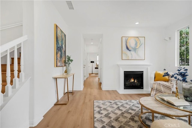 living room with visible vents, recessed lighting, stairway, a lit fireplace, and light wood finished floors