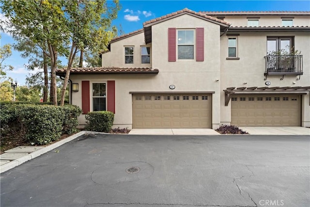 mediterranean / spanish-style home with stucco siding, an attached garage, and a tile roof