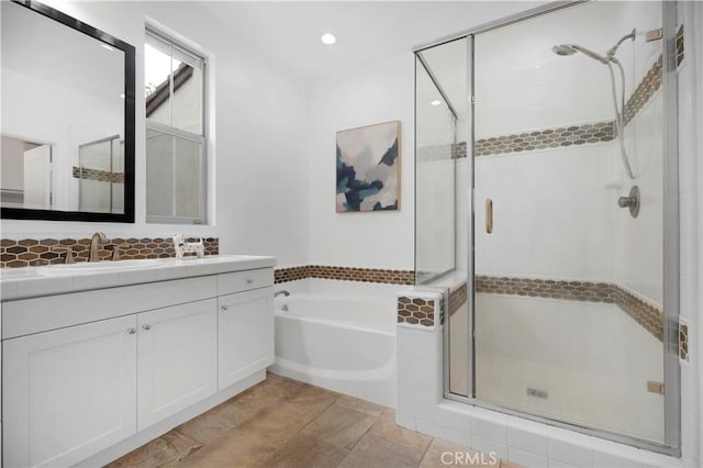 bathroom featuring a stall shower, vanity, and a garden tub