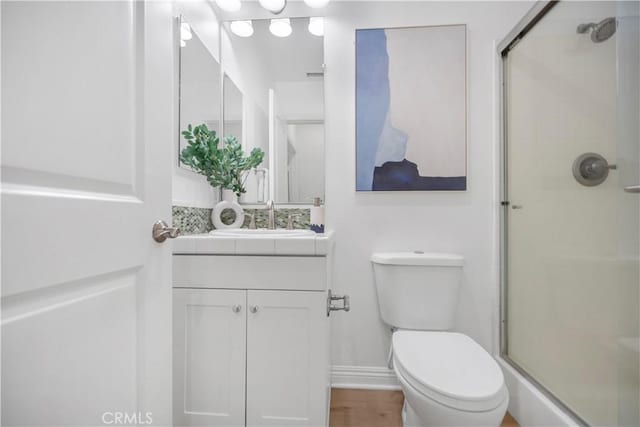 bathroom with vanity, wood finished floors, a shower stall, and toilet