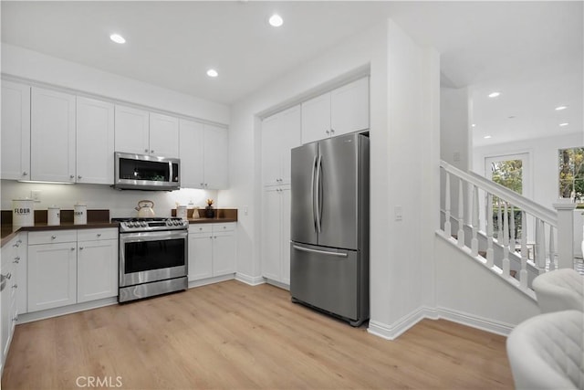 kitchen featuring dark countertops, recessed lighting, stainless steel appliances, light wood-style floors, and white cabinets