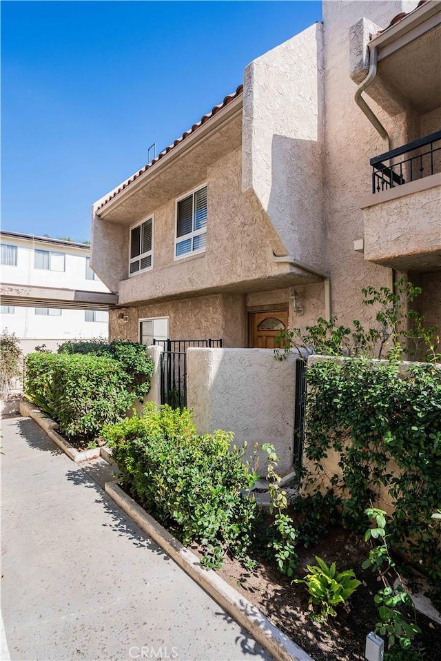 view of front of house featuring a tiled roof, fence, and stucco siding