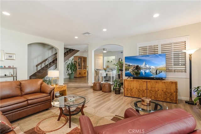 living room featuring stairway, arched walkways, wood finished floors, and visible vents