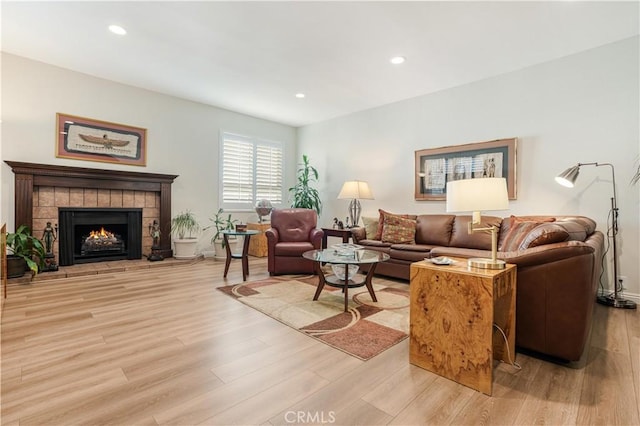 living area featuring light wood-type flooring, a tile fireplace, and recessed lighting