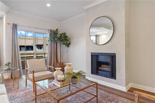 living area featuring crown molding, a fireplace, wood finished floors, and baseboards