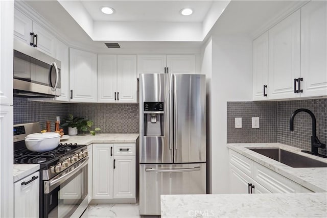 kitchen with marble finish floor, appliances with stainless steel finishes, white cabinets, and a sink