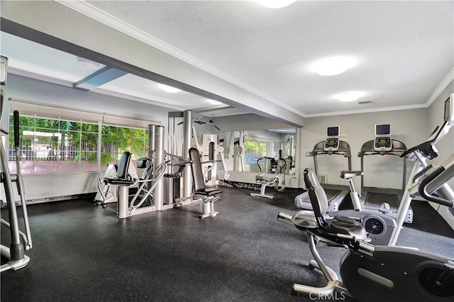 exercise room featuring a textured ceiling, ornamental molding, visible vents, and baseboards