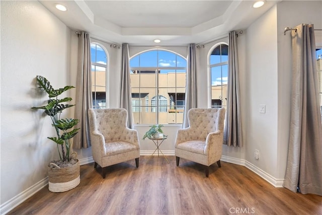 sitting room featuring baseboards, a raised ceiling, wood finished floors, and recessed lighting