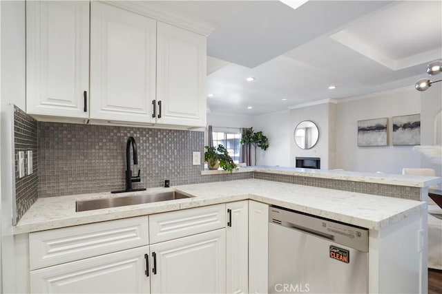 kitchen with white cabinets, backsplash, a peninsula, stainless steel dishwasher, and a sink