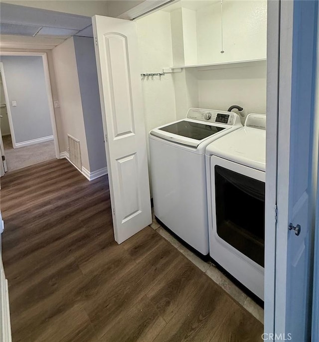 washroom featuring laundry area, dark wood-type flooring, washer and clothes dryer, and baseboards