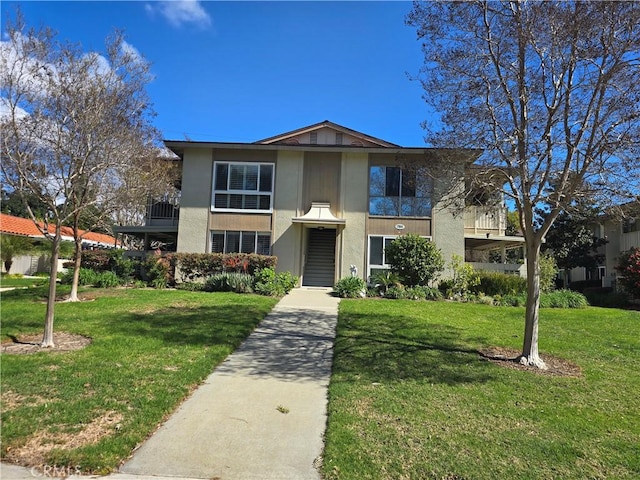 view of front facade with a balcony and a front lawn