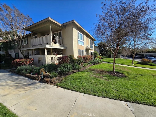 view of property exterior featuring a yard, a balcony, and stucco siding