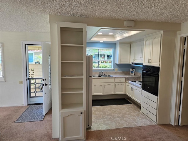 kitchen with white cabinets, black oven, a sink, and dark colored carpet