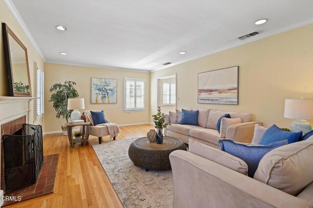 living room with visible vents, ornamental molding, recessed lighting, a fireplace, and wood finished floors