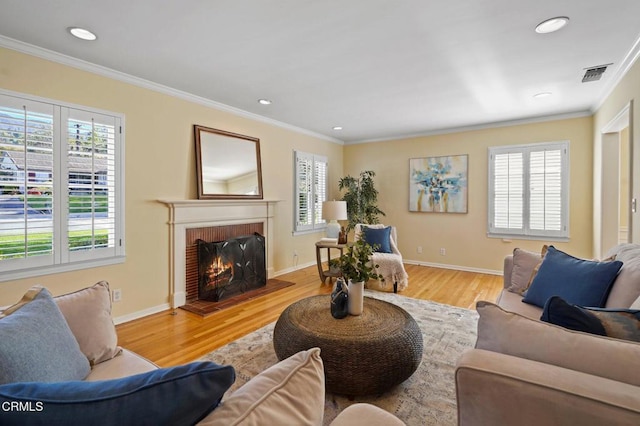 living room with crown molding, a brick fireplace, wood finished floors, and visible vents