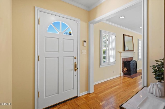 foyer featuring recessed lighting, a fireplace, baseboards, and ornamental molding