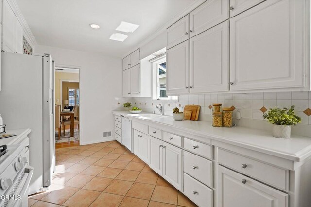 kitchen with white appliances, a sink, decorative backsplash, light countertops, and white cabinets