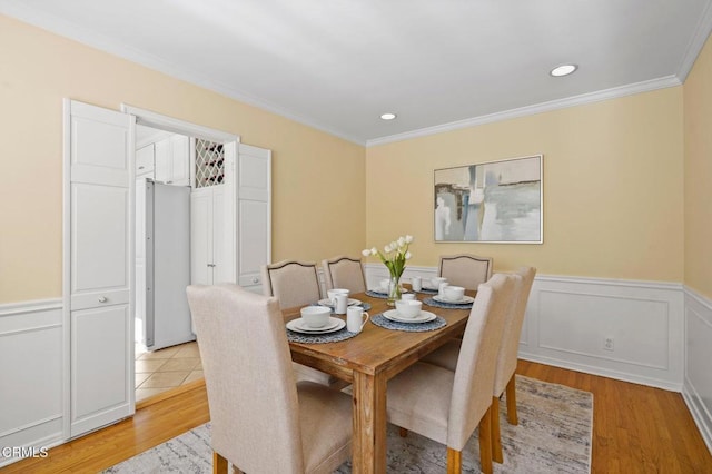 dining room with recessed lighting, light wood-style floors, a wainscoted wall, and ornamental molding