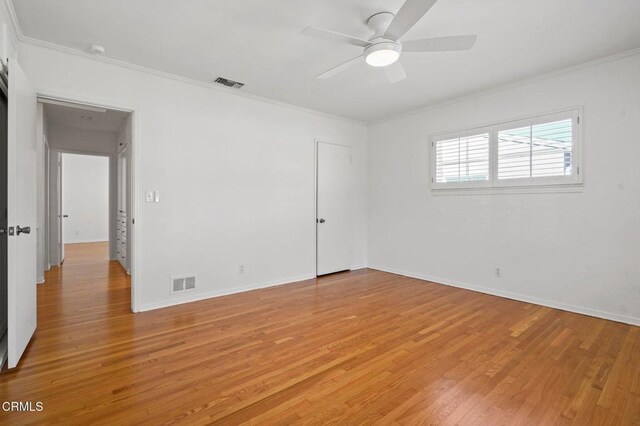 unfurnished room featuring light wood finished floors, visible vents, and ornamental molding