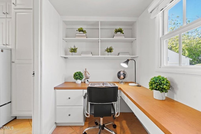 office with light tile patterned floors, built in shelves, and built in study area