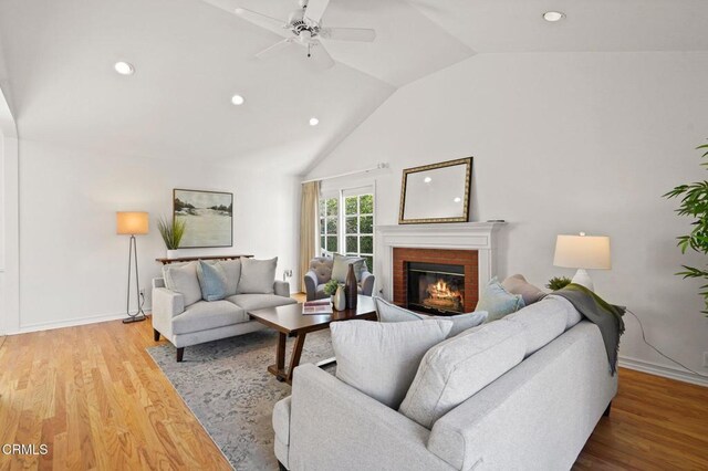 living area with recessed lighting, a brick fireplace, wood finished floors, and vaulted ceiling