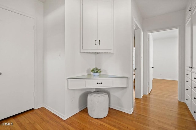 hallway featuring light wood-style flooring and baseboards