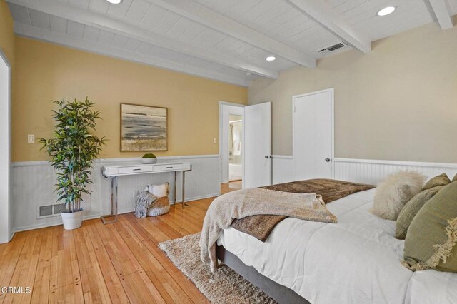 bedroom featuring beamed ceiling, visible vents, a wainscoted wall, and wood-type flooring