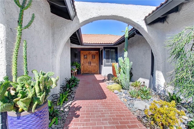 view of exterior entry featuring a tile roof and stucco siding