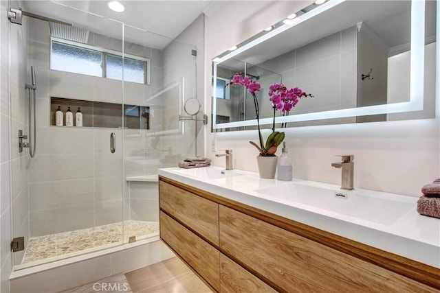 bathroom with double vanity, tile patterned flooring, a shower stall, and a sink