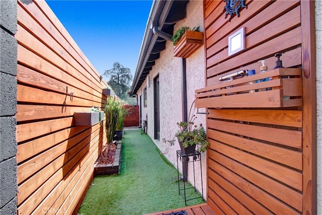 view of side of property with stucco siding, fence, and a yard