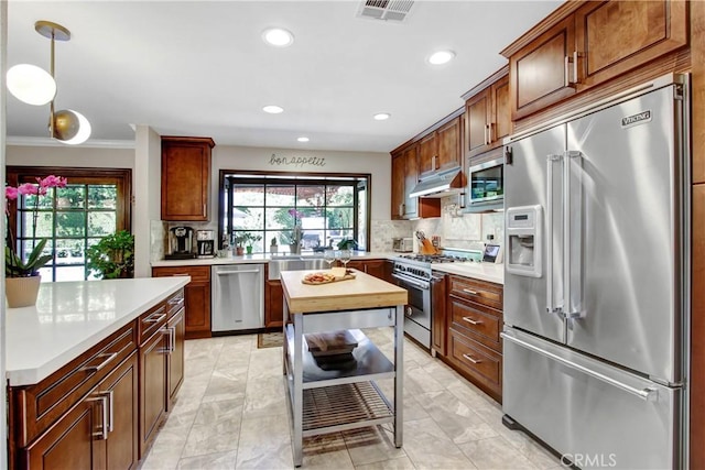 kitchen featuring premium appliances, light countertops, visible vents, and decorative backsplash