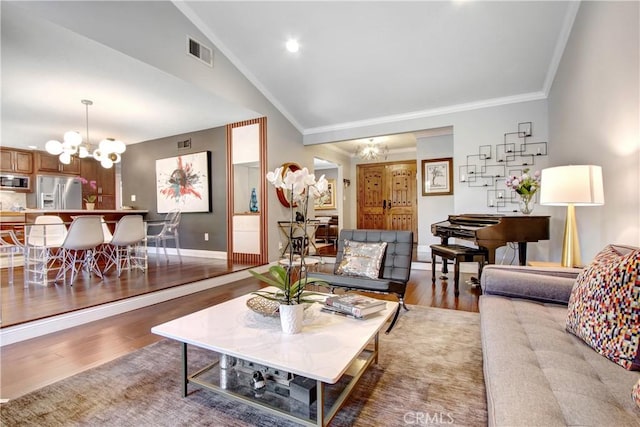 living room with a chandelier, wood finished floors, visible vents, vaulted ceiling, and ornamental molding