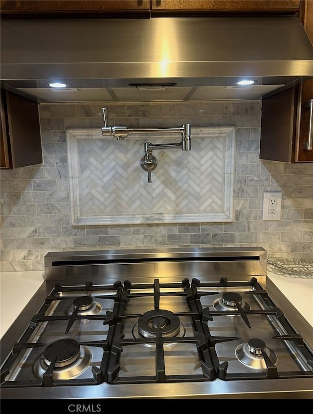 interior details featuring dark brown cabinets, stove, and backsplash