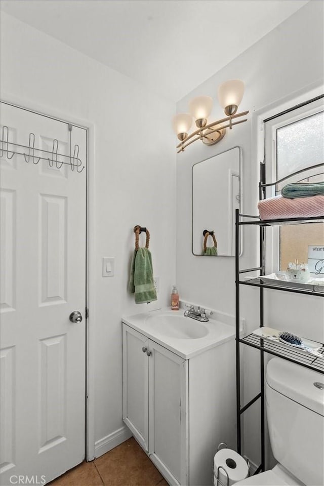 half bathroom with tile patterned flooring, vanity, and toilet