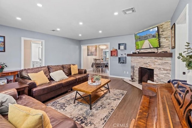 living room featuring recessed lighting, a fireplace, wood finished floors, visible vents, and baseboards