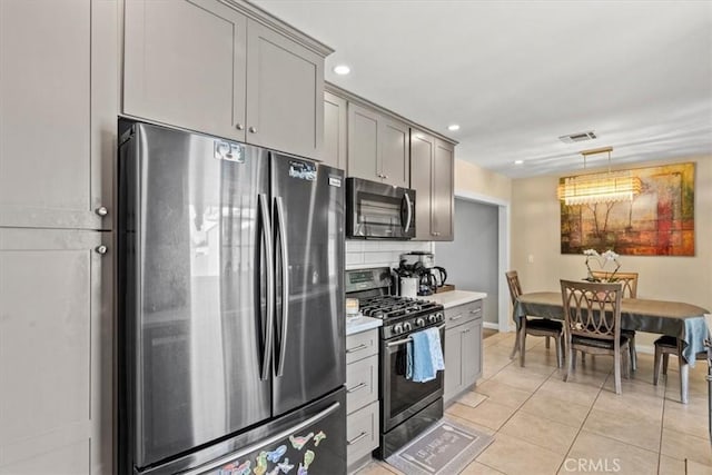 kitchen featuring decorative backsplash, stainless steel appliances, light countertops, gray cabinetry, and light tile patterned flooring