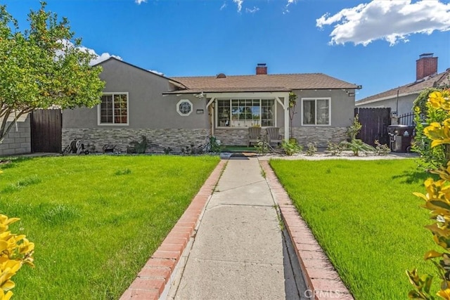 ranch-style home with stone siding, a front yard, fence, and stucco siding