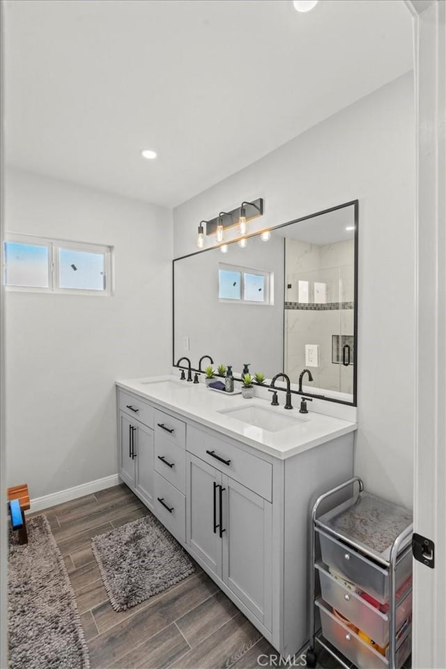 bathroom with a stall shower, wood tiled floor, a sink, and baseboards