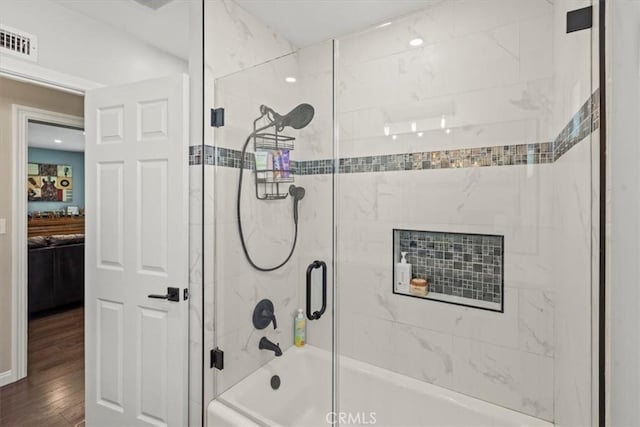 ensuite bathroom with shower / bath combination with glass door, wood finished floors, visible vents, and connected bathroom