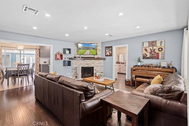 living area with dark wood-type flooring, recessed lighting, visible vents, and a fireplace