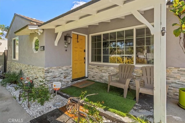 doorway to property featuring stone siding and stucco siding